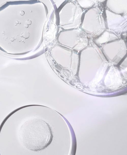 Macro shot of clear cosmetic gels and liquid bubbles, featuring light and shadow play on a white surface, ideal for beauty product advertising.