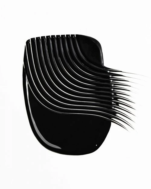 Close-up of a smear of black mascara. The makeup product is swiped in an arching pattern across a plain white surface. 