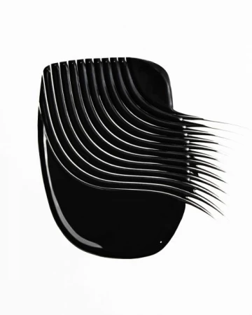 Close-up of a smear of black mascara. The makeup product is swiped in an arching pattern across a plain white surface. 