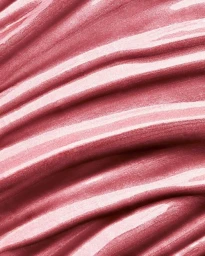 Close-up macro shot of glossy pink cosmetic cream or lipstick texture with sweeping ridges and highlights.