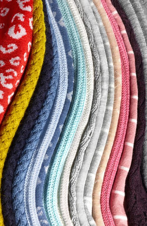 Close-up of colorful knitted fabrics with various patterns and textures, including cable knits, animal prints, and stripes.