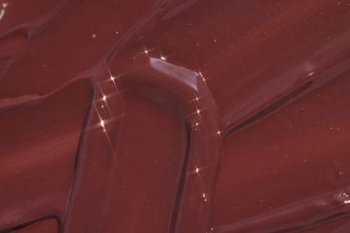 Close-up shot of glossy, textured brown material with light reflections, creating abstract patterns. The surface shows depth and shine.
