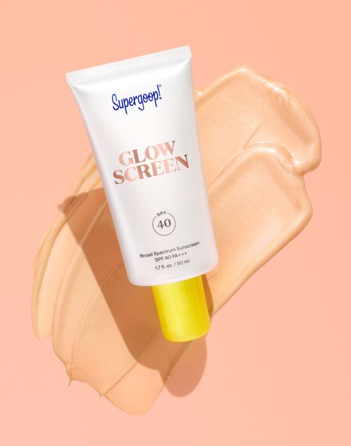 Supergoop! Glow Screen SPF 40 sunscreen tube on a beige swatch, presented on a pale pink background, in a beauty product shot.