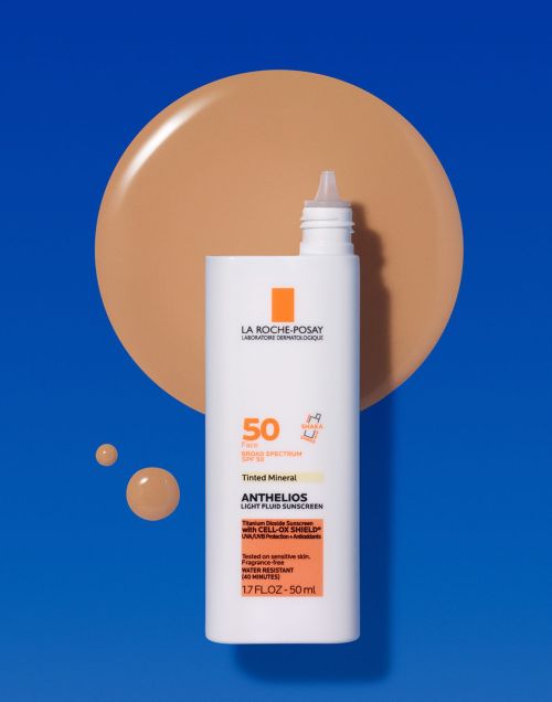 La Roche-Posay Anthelios sunscreen bottle with tinted mineral light fluid SPF 50, next to a matching swatch of liquid foundation on blue.