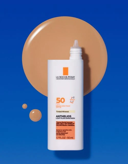 La Roche-Posay Anthelios sunscreen bottle with tinted mineral light fluid SPF 50, next to a matching swatch of liquid foundation on blue.