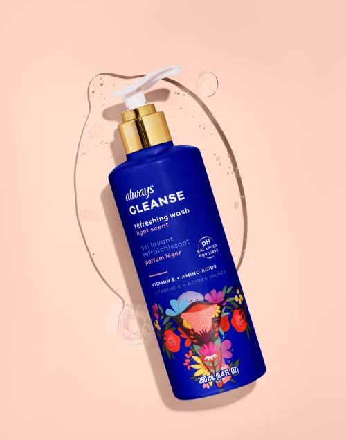 Bottle of Always Cleanse Refreshing Wash on peach background with a shiny water droplet trail. Feminine hygiene product.