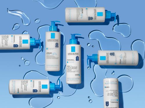 A flat lay studio shot features multiple La Roche-Posay skincare bottles against a light blue background with simulated water droplets for beauty advertising.