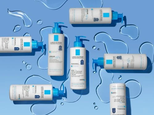 A flat lay studio shot features multiple La Roche-Posay skincare bottles against a light blue background with simulated water droplets for beauty advertising.
