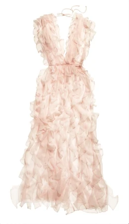 A pale pink dress with ruffles hangs on a hanger against a white backdrop, showcasing its layered design and soft color palette.