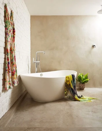Contemporary bathroom features a standalone white bathtub, neutral wall tones, a hanging floral dress, and indoor potted plants.