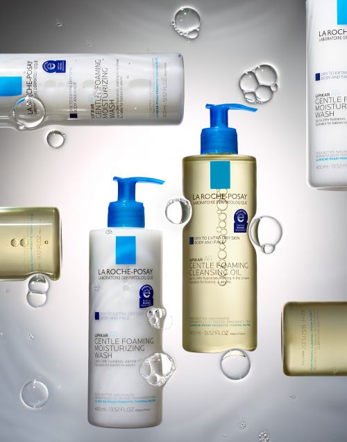 La Roche-Posay gentle foaming cleansers: moisturizing wash and cleansing oil with water droplets against a gradient grey background.