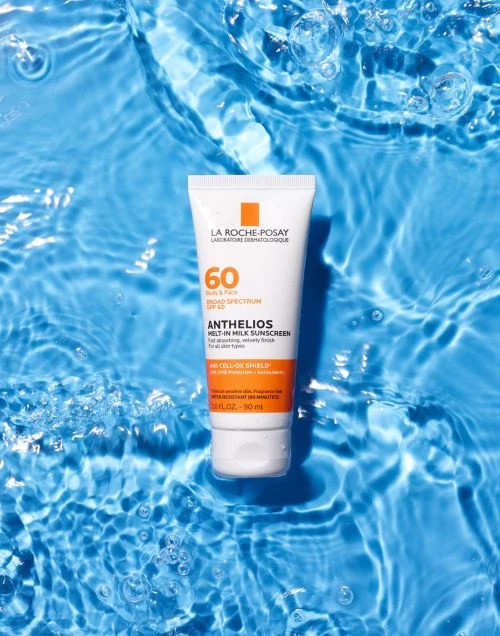 La Roche-Posay Anthelios sunscreen bottle floating in clear blue water with light reflections and water droplets, ideal for summer skincare.