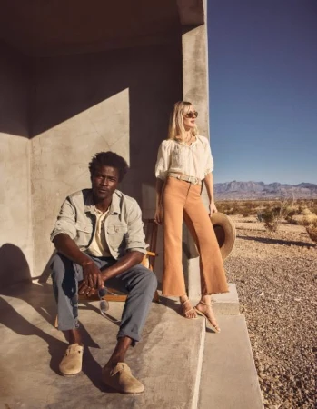 Man seated on concrete porch steps and woman standing beside him in desert landscape styled by Tennille Yamashita.