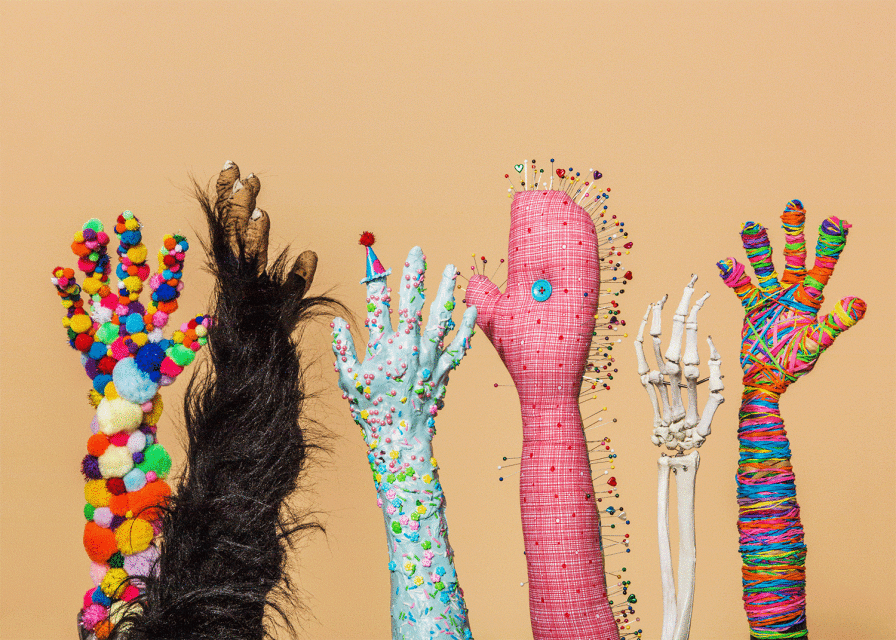Creative studio shot of five decorated human-like hands, each with unique themes like fur, pompoms, pins, and colorful bands, on beige backdrop.