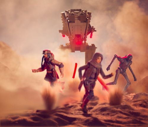 Two figures run across a desert landscape away from a large gray walker, with a robotic figure visible in the background.