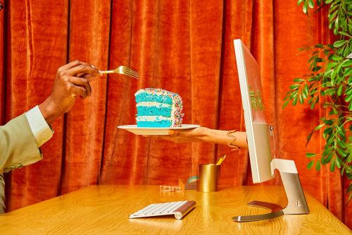 Hands reach out from a computer screen to offer a slice of cake, highlighting digital connectivity and food presentation.