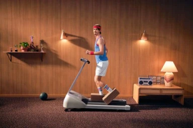 Man in retro athletic wear using a treadmill in a wood paneled room with vintage furniture and warm lighting