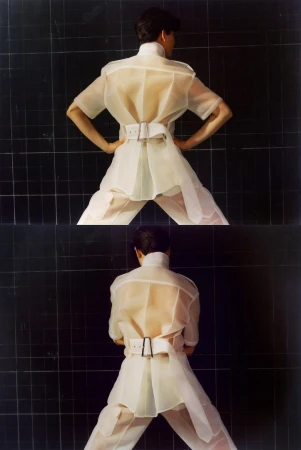 Two images of a person in a white, translucent short-sleeved shirt, belt and pants, standing with hands on hips against a black tile wall.