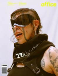 Close-up portrait of a person with facial tattoos wearing oversized wrap-around sunglasses and black clothing by Eric Chakeen.