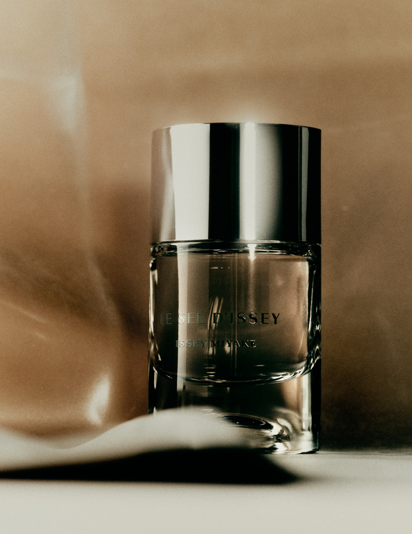 Bottle of L'Eau d'Issey Eau Nuit Magnetique fragrance with silver cap and translucent bottle on bronze satin background. Still life.