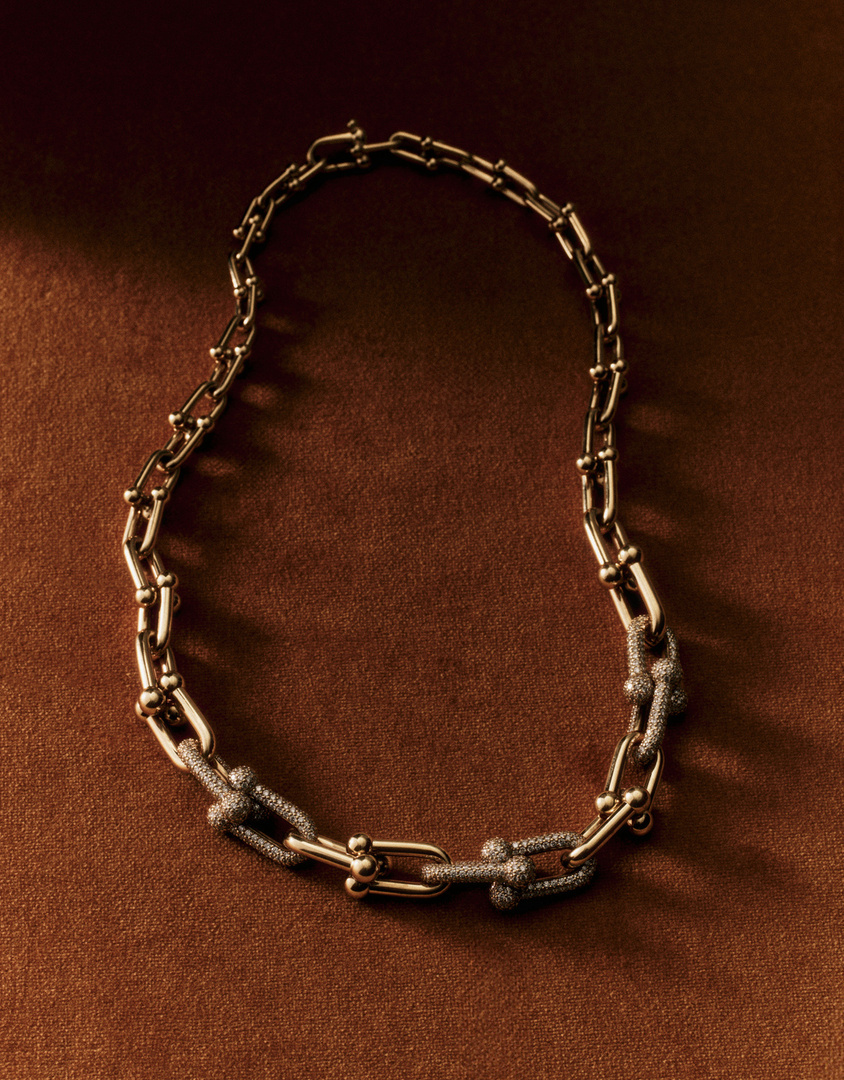 Gold chain link necklace on a brown background. Jewelry close-up shot showcasing the design and material. Fashion accessory, chain-link style.
