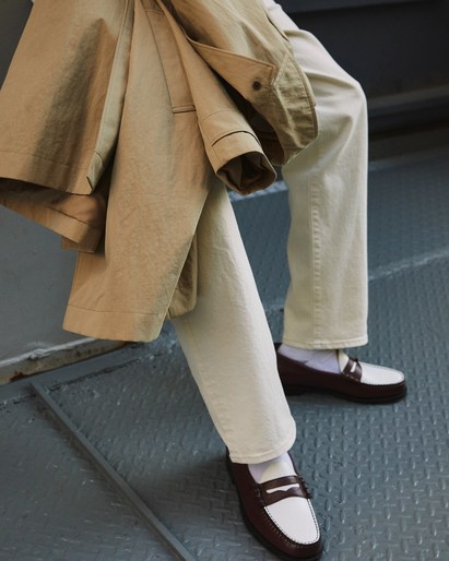 Fashionable look: Person in light denim jeans, brown and white penny loafers, white socks, and a tan jacket.