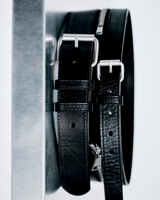 Close-up of a black leather bag with silver zippers and buckle straps against a white backdrop.