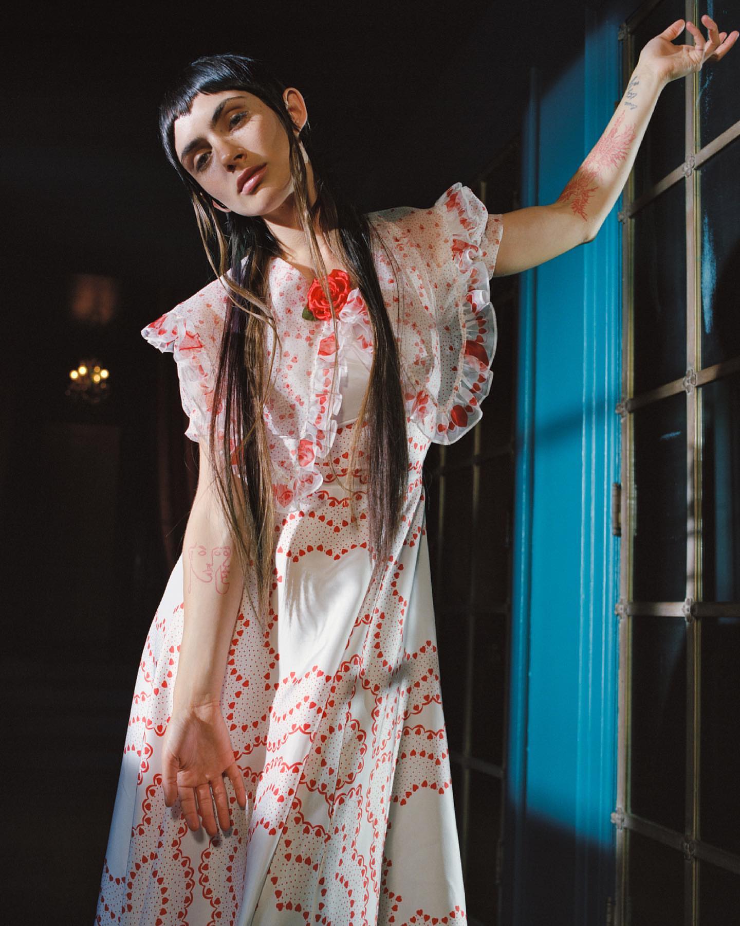 Woman in a white and red patterned dress posing next to a bright blue window frame by photographer Daria Kobayashi Ritch.
