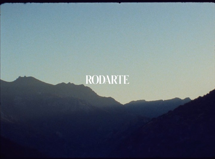 Mountain range landscape under a gradient sky with the white Rodarte brand logo centered.