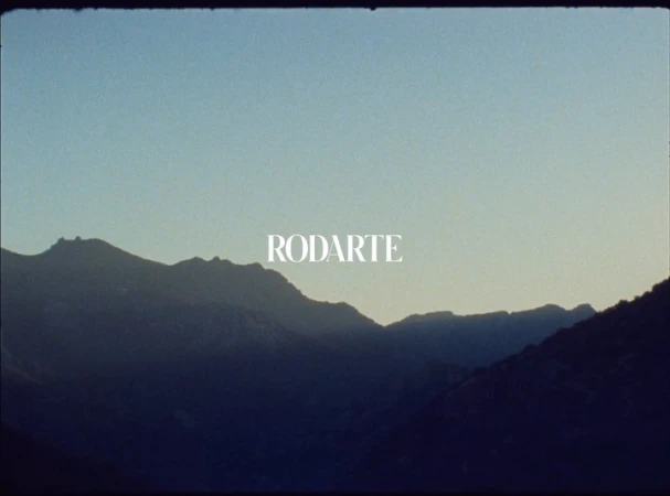 Mountain range landscape under a gradient sky with the white Rodarte brand logo centered.
