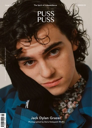 Magazine cover portrait of Jack Dylan Grazer in a blue plaid shirt and floral undershirt, hand near his face, with brand "PUSS PUSS" text.