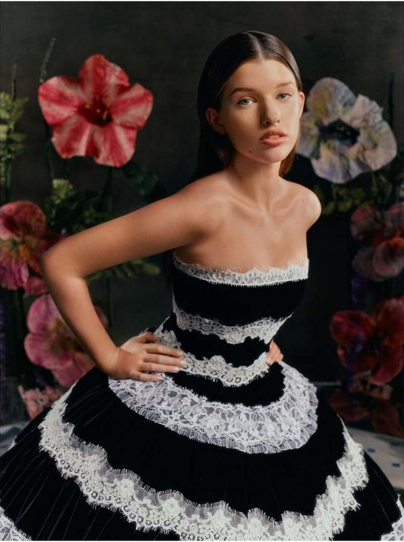 Young woman in black and white strapless gown with floral backdrop. Fashion shot with elegant textures and a portrait orientation.