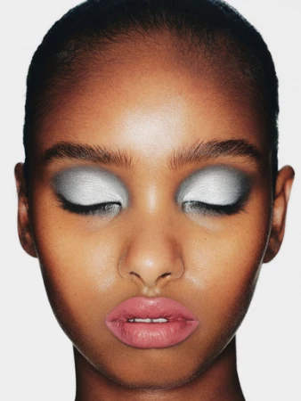 Close-up portrait of a woman with metallic silver eyeshadow and pink lips against a plain white background