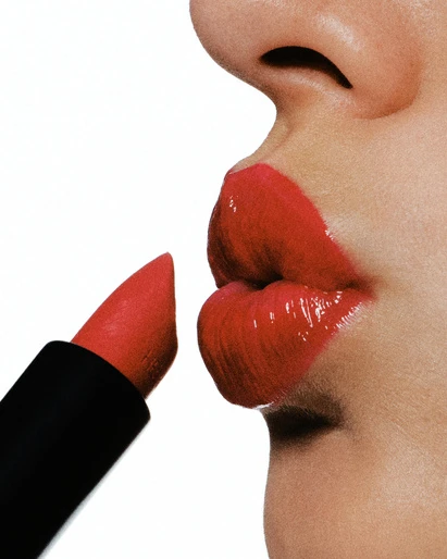 Close-up of woman applying bright red lipstick, against a stark white background, beauty product shot. Cosmetics and makeup.