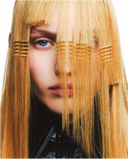 Close-up portrait of a woman with long blonde hair covering her eyes, featuring distinctive horizontal crimped sections across strands
