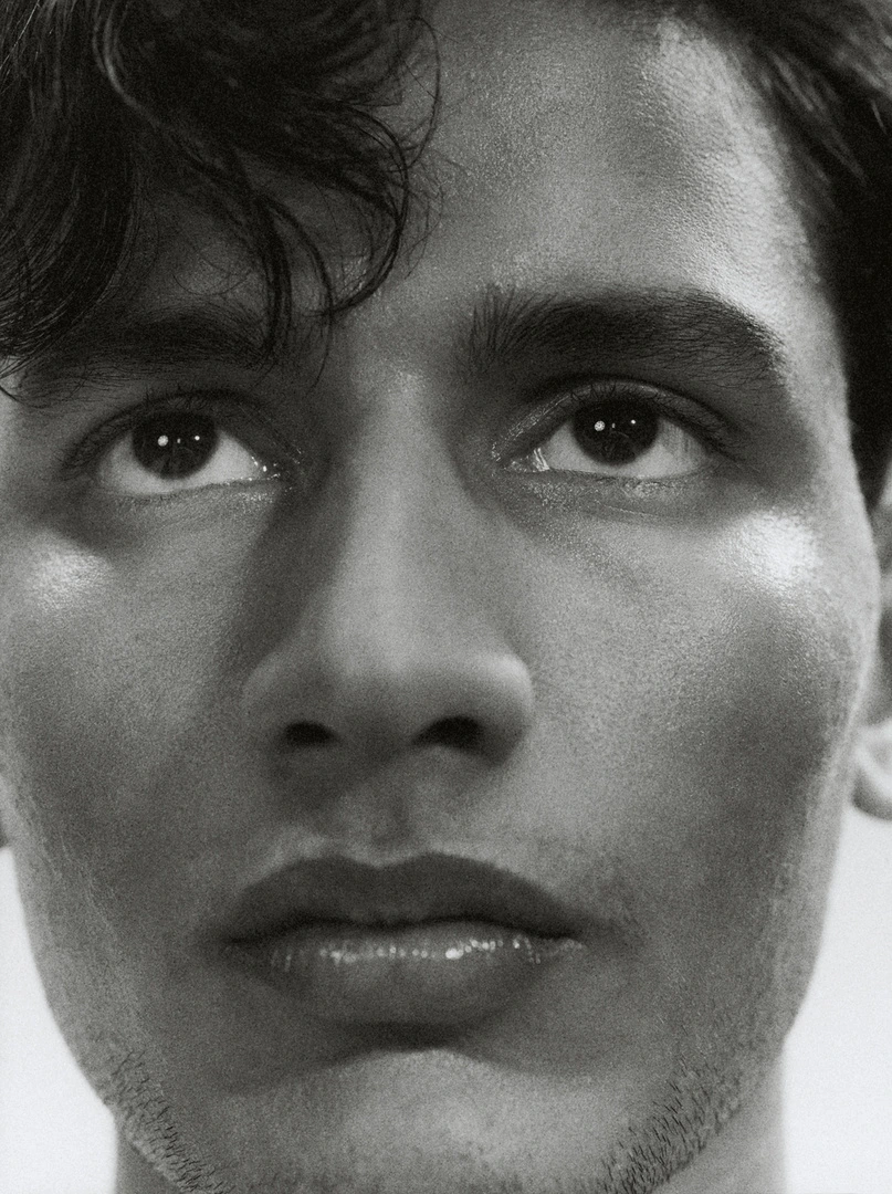 Close-up monochrome portrait of a young man with dark curly hair looking upward by photographer Sam Wilson