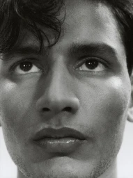 Close-up monochrome portrait of a young man with dark curly hair looking upward by photographer Sam Wilson