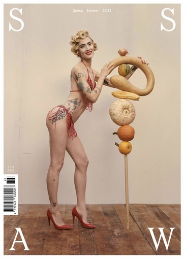 Magazine cover featuring a woman in a red bikini next to a stack of gourd fruits, showcasing editorial style and summery, playful aesthetics.