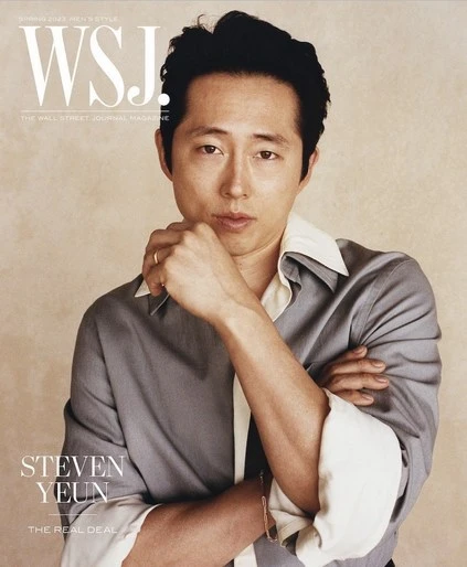 Steven Yeun portrait for WSJ. Magazine cover, wearing gray shirt, hand near face, against light beige background, portrait orientation.