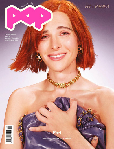 Magazine cover featuring a smiling woman with orange hair, wearing a gold necklace and earrings, holding a purple chain bag.