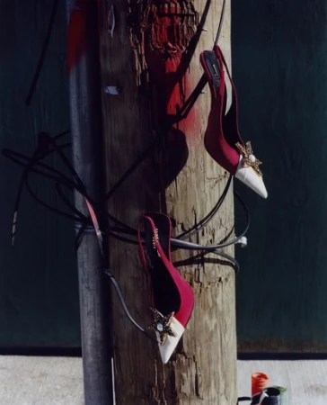 Elegant red and white slingback heels adorned with a star embellishment, stylishly hanging from a weathered wooden utility pole.