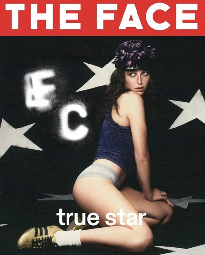 Magazine cover featuring a model in a blue top and briefs kneeling against a black background with white stars and bold typography.