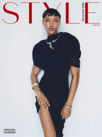 Model in a black dress wearing metallic bracelets and a sculptural necklace against a white background