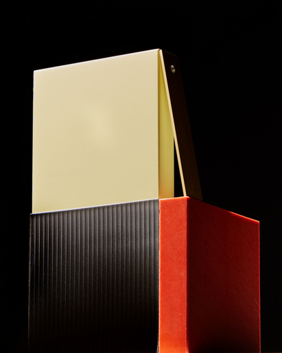 Geometric color block product photography featuring a tan block on a black corrugated block on a red block against a black backdrop.