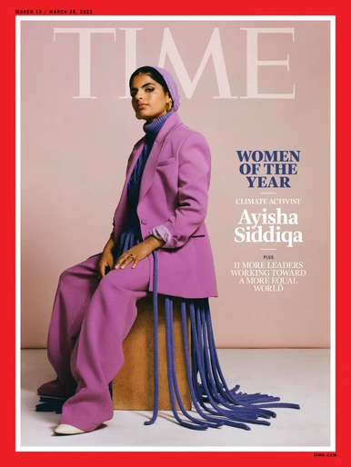 Ayisha Siddiqa seated on a wooden stool wearing a purple suit and head covering against a neutral background for Time magazine.