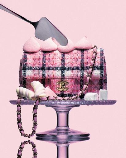 Pink Chanel handbag displayed on a cake stand with marshmallows and a silver cake server against a soft pink background.