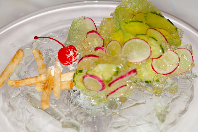 Artistic food presentation featuring french fries, cherry, and radishes on ice, creating a visually striking and unconventional dish.