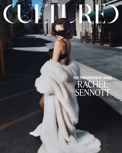 Magazine cover featuring Rachel Sennott in a black bra, mask, and large fur coat, photographed in an outdoor urban setting.