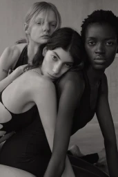Three female models posing closely together in black apparel against a neutral background in Los Angeles.