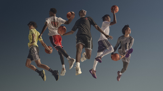 Five adult males leaping in the air playing with basketballs against a plain dark blue background, wearing athletic attire and sneakers.